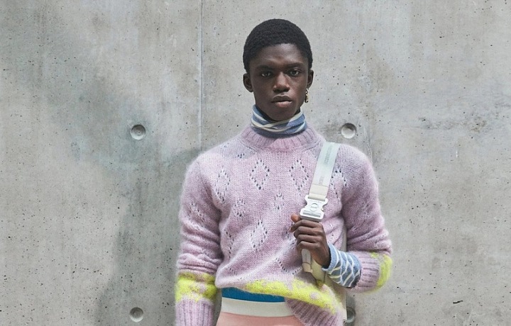 Muž v bílých kalhotách a barevném svetru Dior