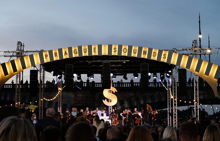 Hudebníci hrající na pódiu, nad nimi nápis Prague Sounds