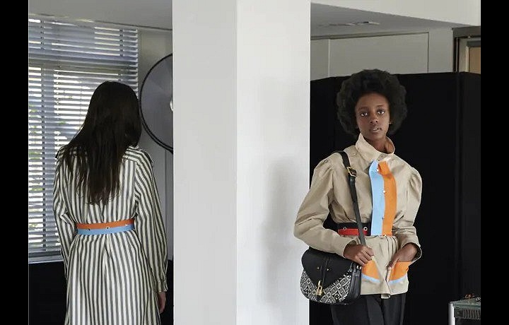 Žena v béžovém trenčkotu a černých kalhotách Louis Vuitton