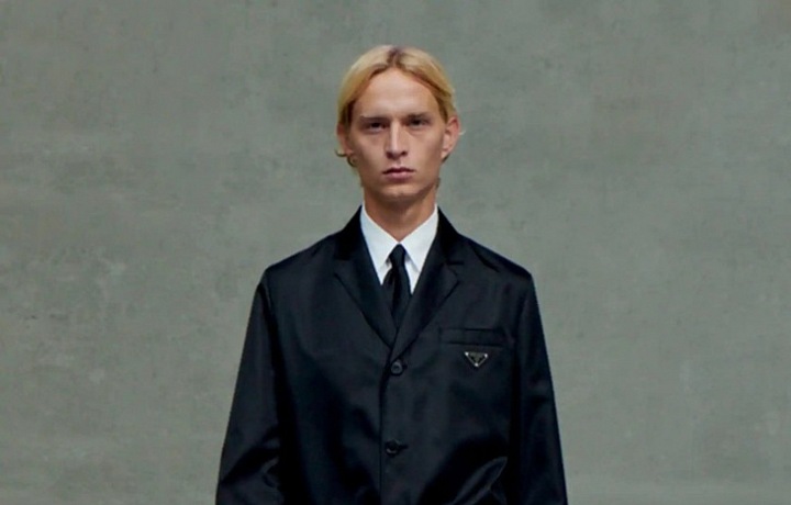 Muž v černém obleku a kabátu Prada