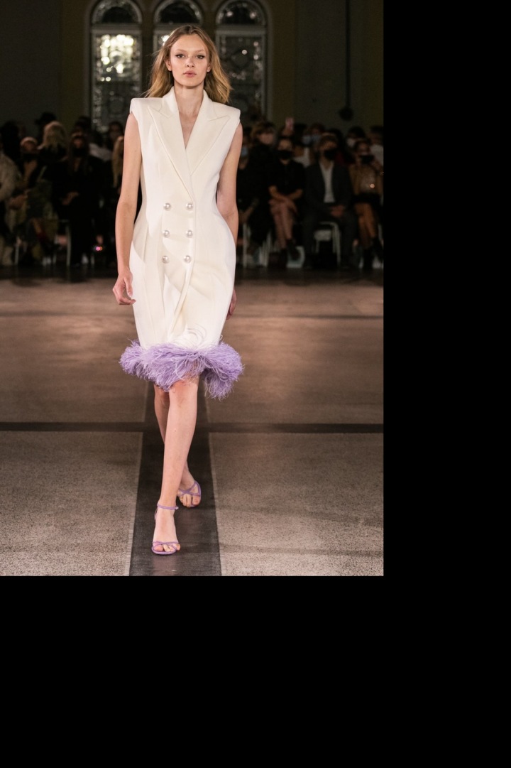 Modelka má na sobě bílé šaty s pírky od Vandy Jandy