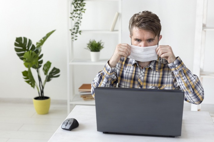 Muž má na sobě při práci roušku