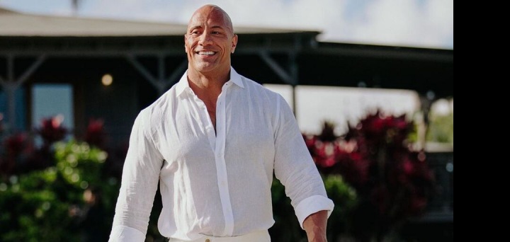 Dwayne Johnson v bílé košili a kalhotách