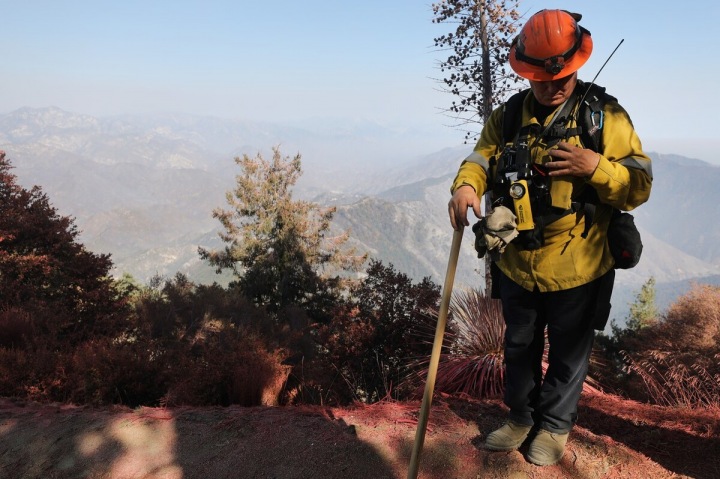 Hasič stojí před poničenou krajinou