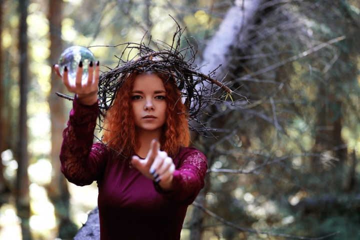 Krásná dívka, věštkyně s křišťálovou koulí v ruce se dívá směle do budoucnosti