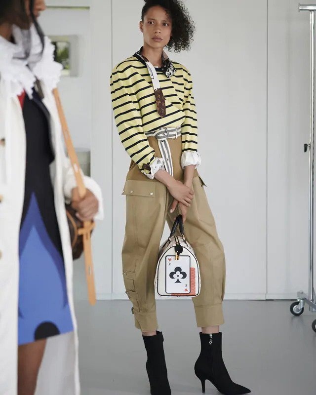 Žena v pruhovaném topu a béžových kalhotách Louis Vuitton