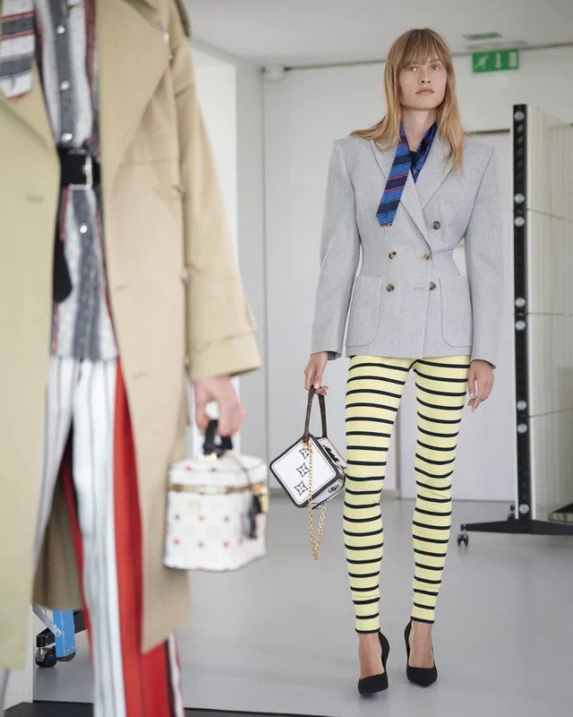 Žena v šedém saku a pruhovaných kalhotách Louis Vuitton