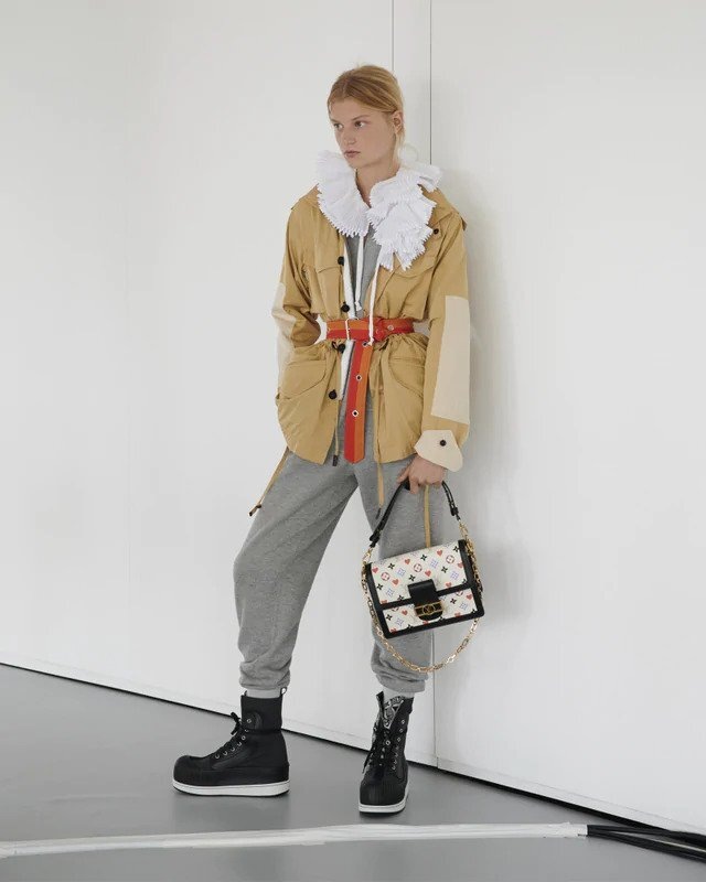 Žena v béžové bundě a šedých teplácích Louis Vuitton