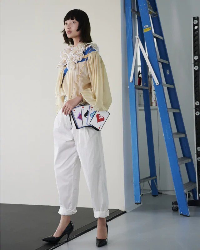 Žena ve žluté halence a bílých kalhotách Louis Vuitton