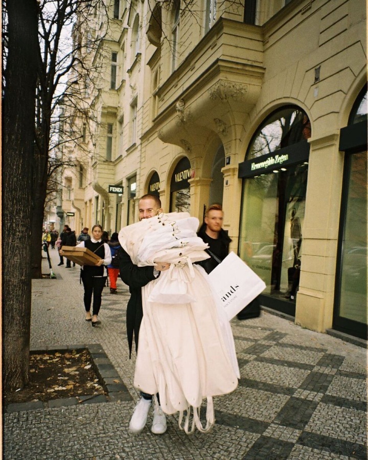 Lukáš Macháček v ulici s oblečením. 