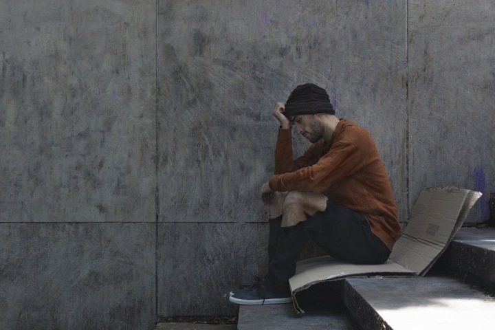 Muž bez domova sedí na ulici