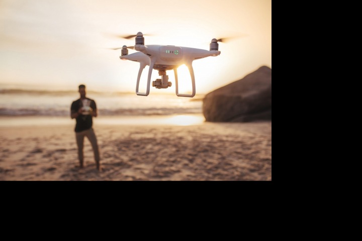 Muž na pláži s dronem