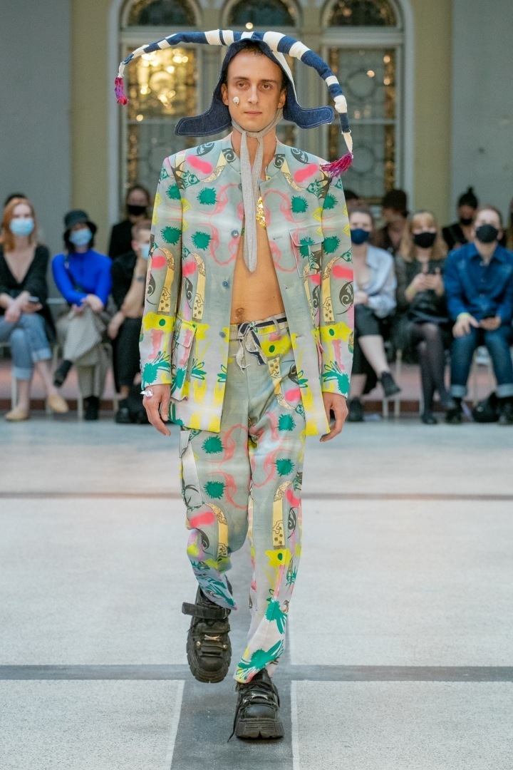 Muž v kašpárkovské čepici a barevném outfitu