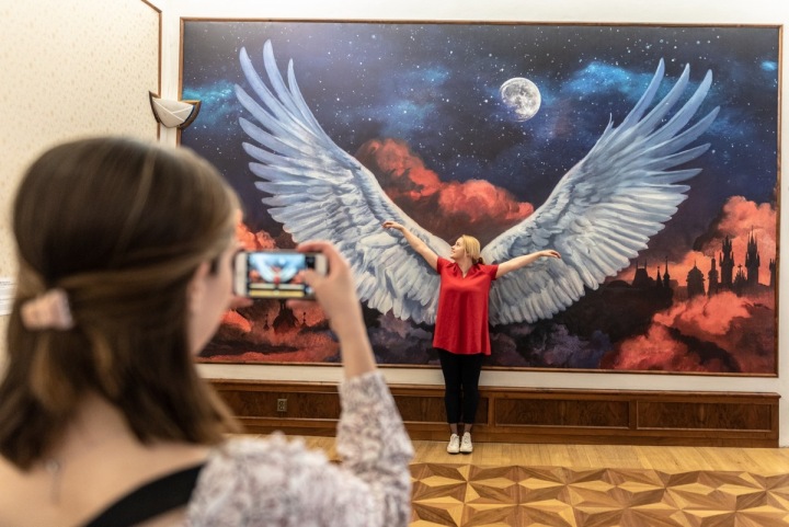 Dívka v muzeu se nechává fotit před obrazem s velkými křídly