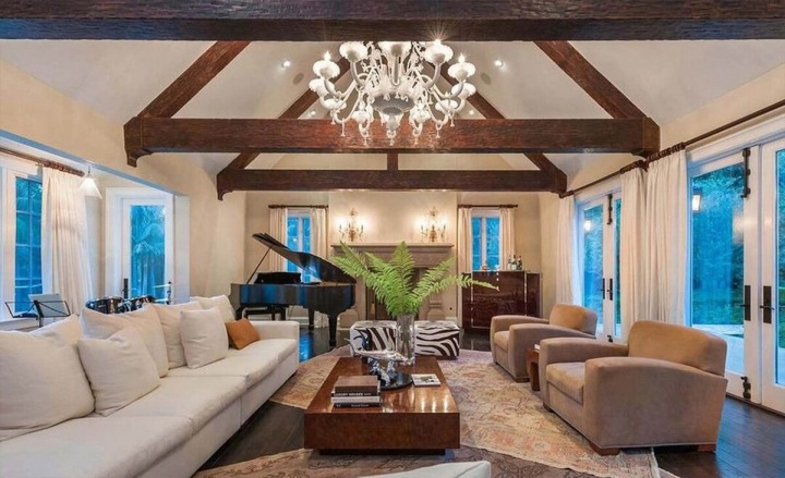 Obývací pokoj se světlými křesly a dřevěnými trámy pod stropem