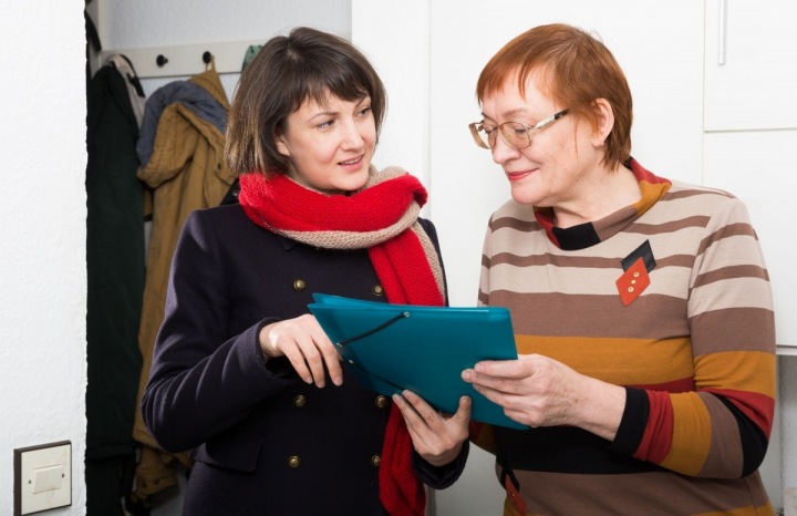 Mladší žena pomáhá starší s dokumenty 