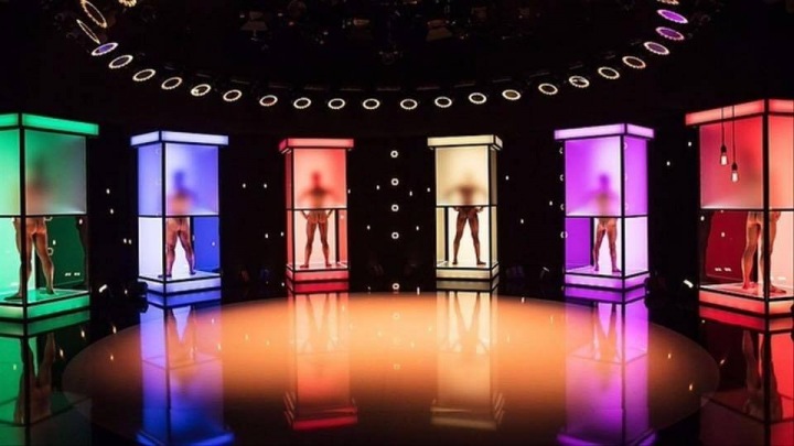 Šest nahých mužů v barevných kabinkách.