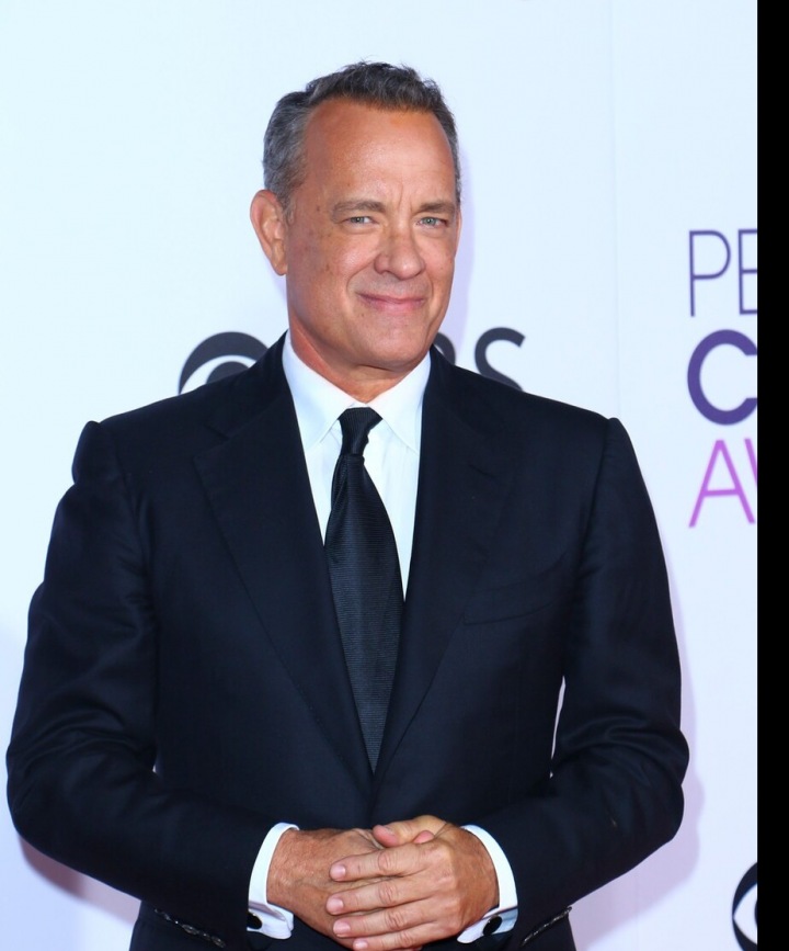 Tom Hanks stojí v tmavém obleku