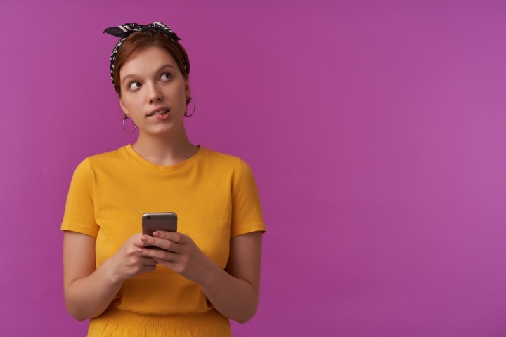 Zamyšlená dívka s mobilem v ruce