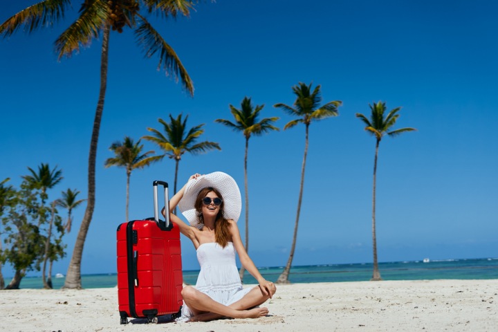 Žena na pláži s kufrem.