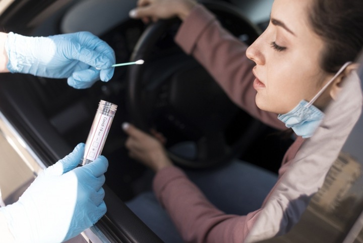 Žena sedí v autě a je jí prováděn test na covid-19