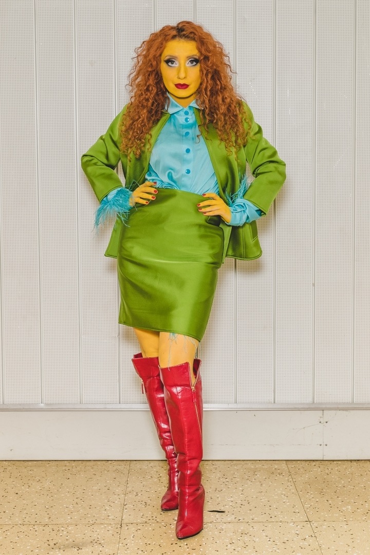 Žena v zeleném kostýmku a modré halence Lukáše Krnáče