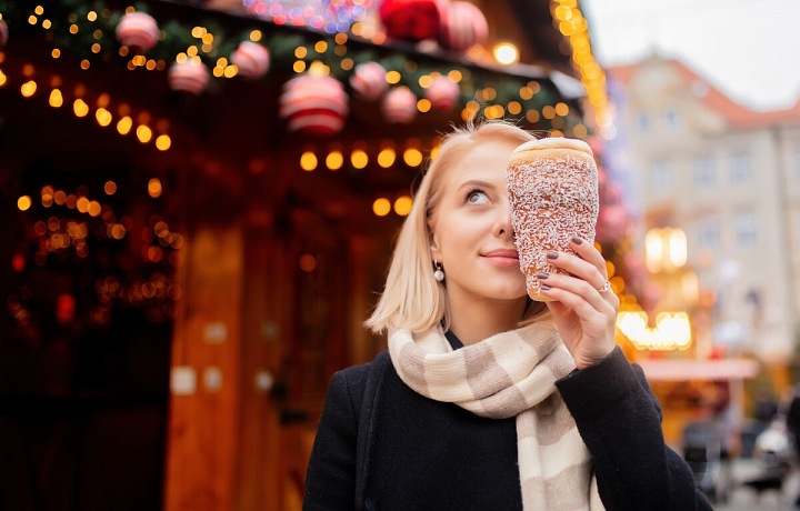 Dívka na vánočních trzích s trdelníkem.