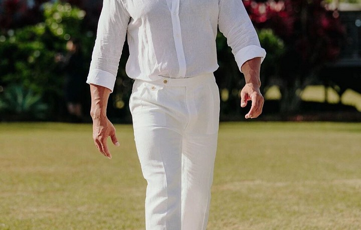 Dwayne Johnson v bílé košili a kalhotách