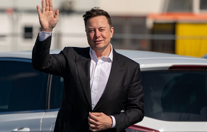 Elon Musk stojí ve tmavém obleku