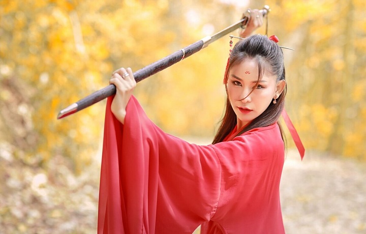 Krásná Mladá čínská dívka v červeném hábitu s mečem