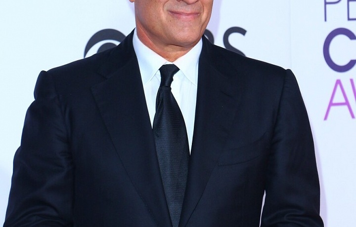 Tom Hanks stojí v tmavém obleku