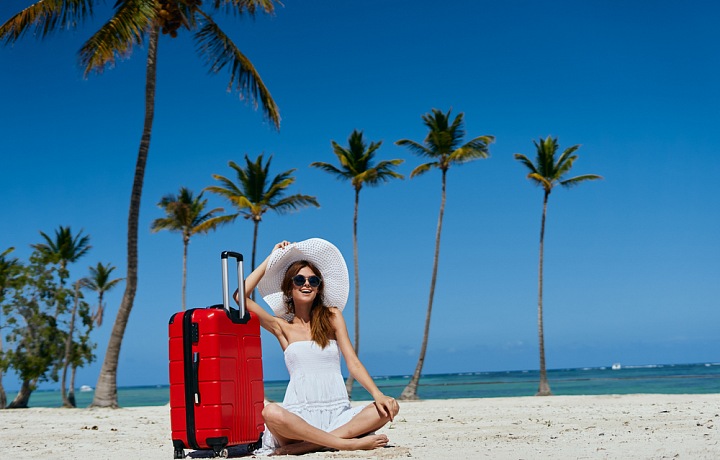 Žena na pláži s kufrem