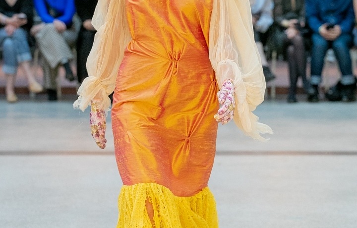 Žena v oranžových šatech a šedé čepici